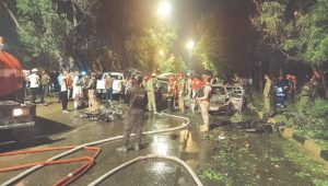 RESCUE workers, firefighters and security officials examine the wreckage of cars caught up in the explosion, which took place near Karachi airport on Sunday night