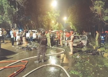 RESCUE workers, firefighters and security officials examine the wreckage of cars caught up in the explosion, which took place near Karachi airport on Sunday night